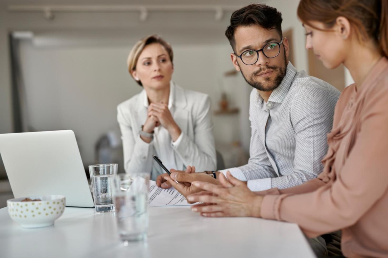 Espacio de trabajo colaborativo con documentos financieros y café sobre mesa de madera
